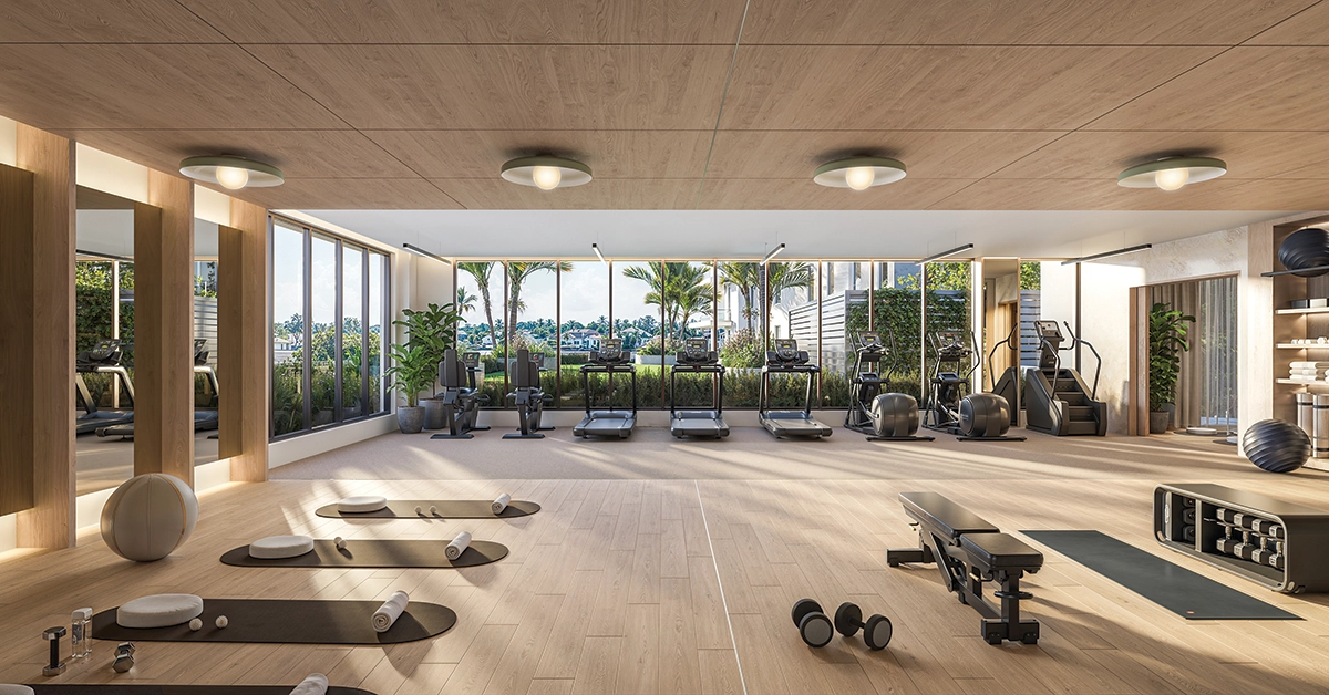 Modern fitness center with cardio machines, yoga mats, free weights, and garden views