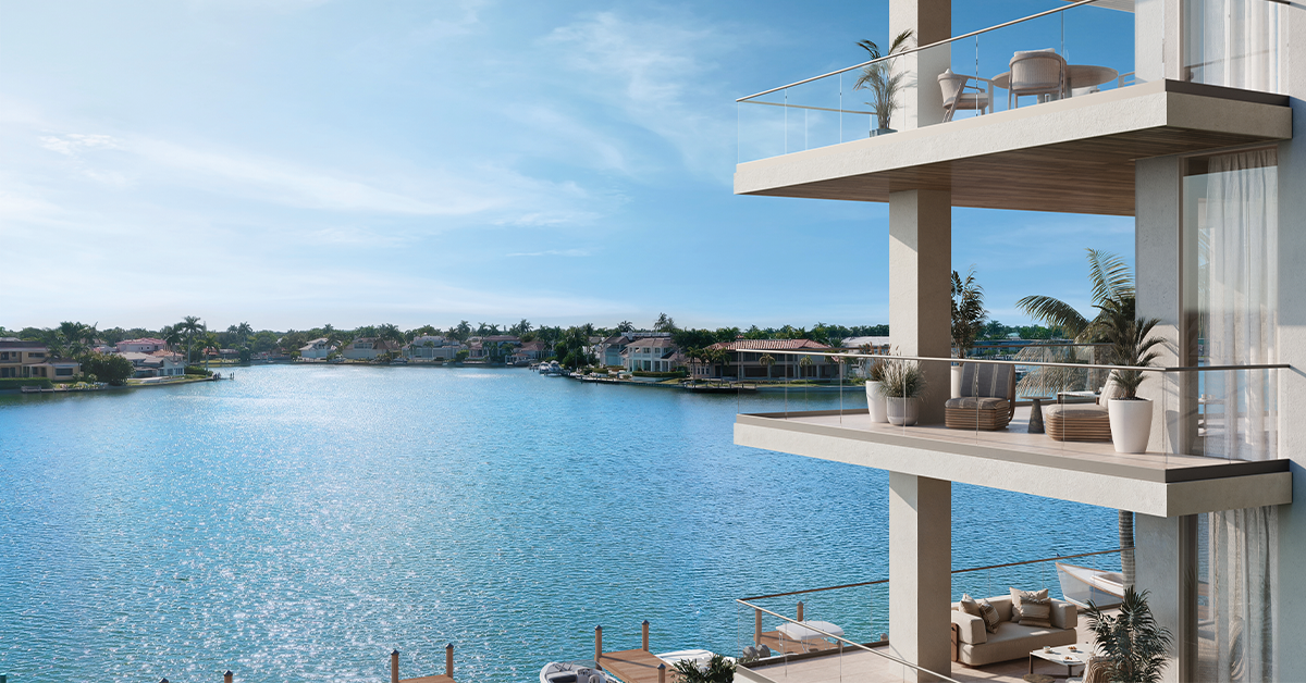 Waterfront condominium balcony overlooking a calm bay with palm-lined shoreline