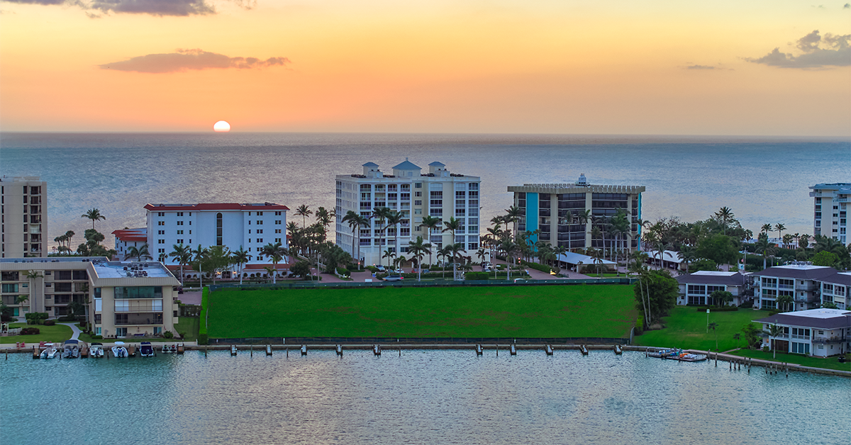 Aerial view of coastal waterfront residences with palm trees at sunset