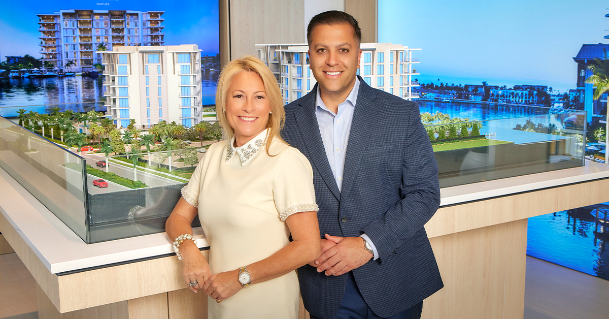 Joe and jictoria professionals stand beside a model of a waterfront residential development.