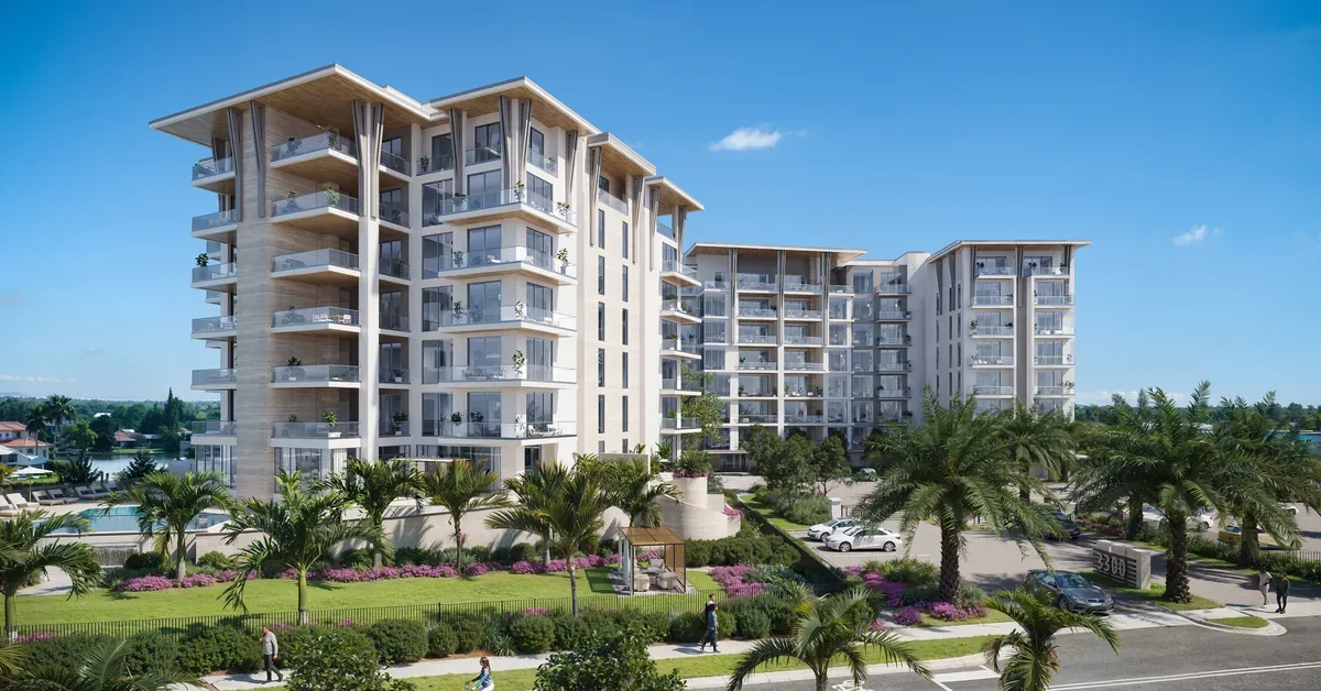 Luxury waterfront condominium complex with modern architecture, lush tropical landscaping, and private balconies under a clear blue Florida sky.